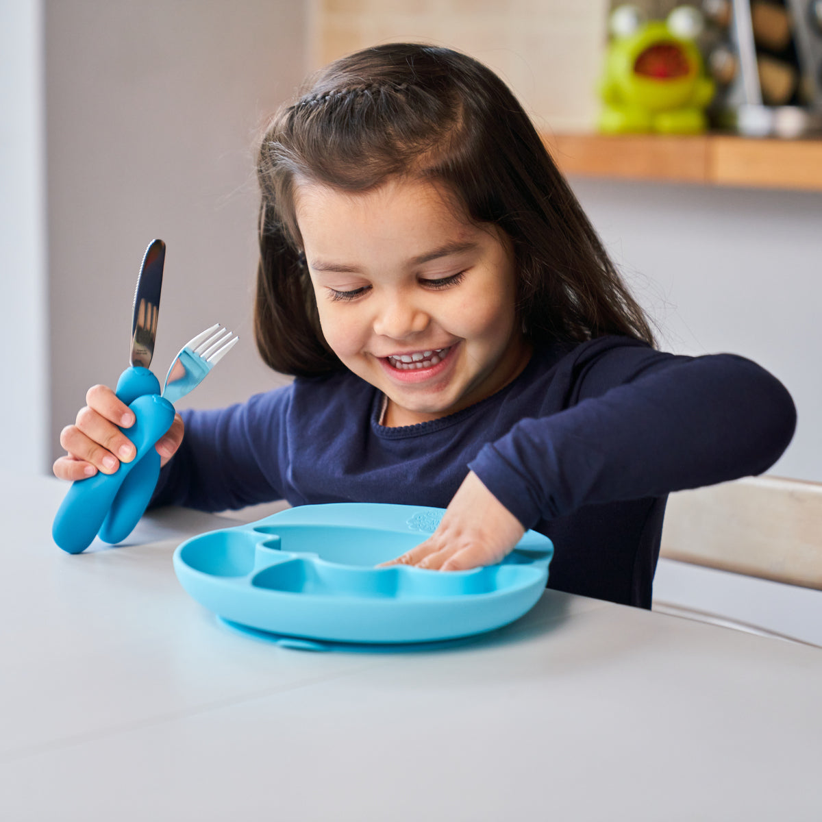 Kind benutzt kindgerechtes blaues Besteck und Teller aus sicherem Material Essen & Trinken für Kinder