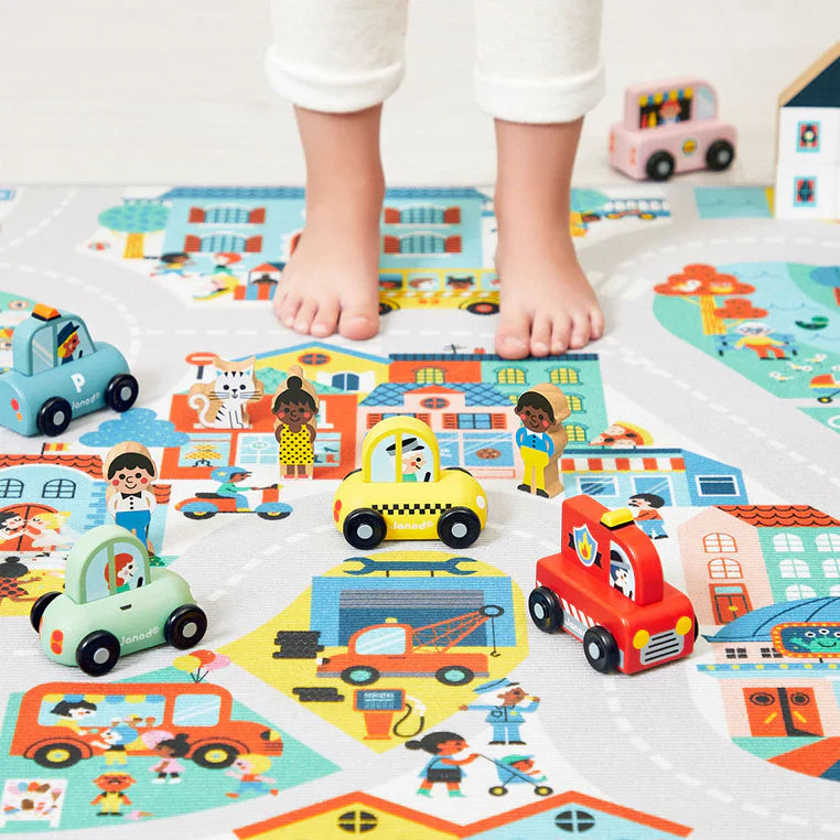 Lächendes Baby liegt auf grüner weicher Spielmatte mit Tier- und Naturmotiven aus Stoff