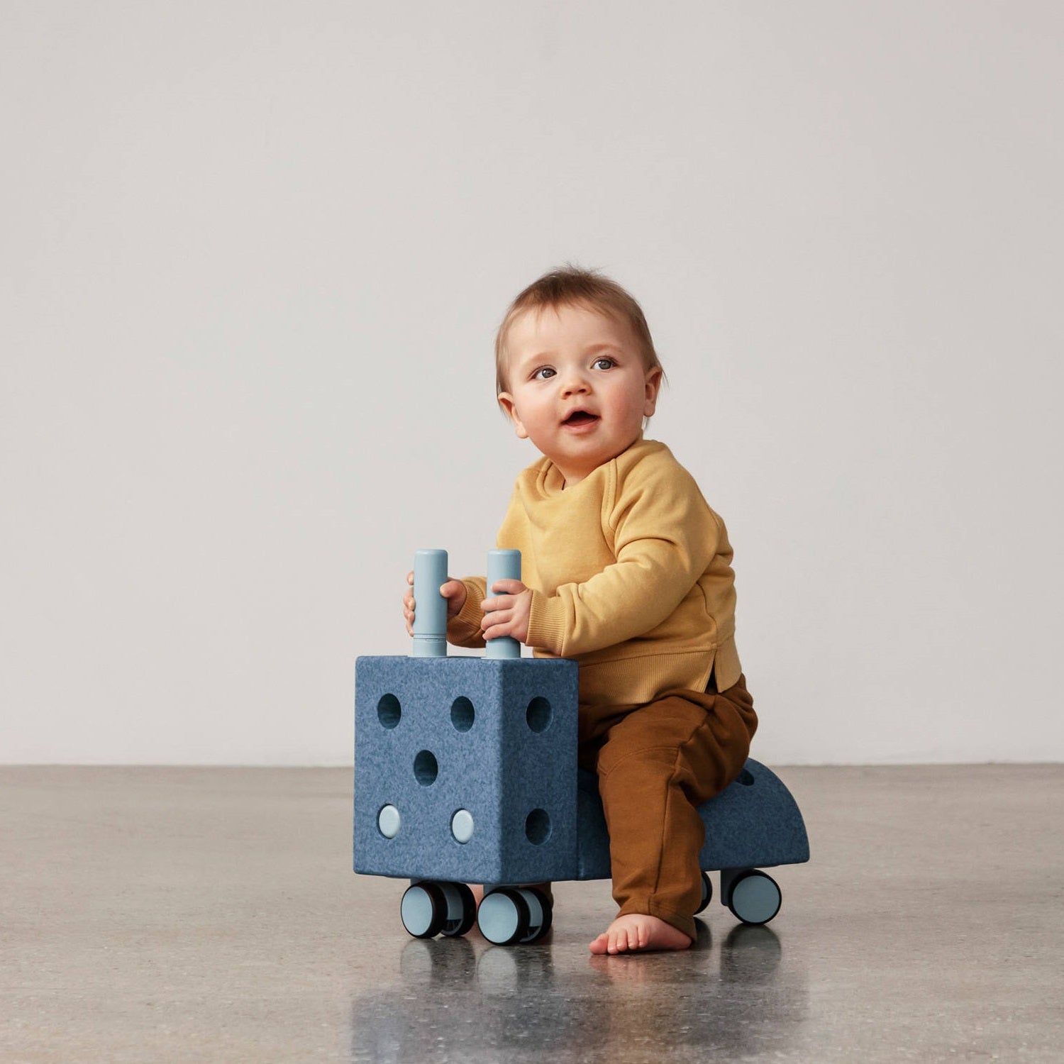 Baby sitzt auf blauem Rutschfahrzeug und spielt mit Schiebetieren, sicher und stabil zum Lernen