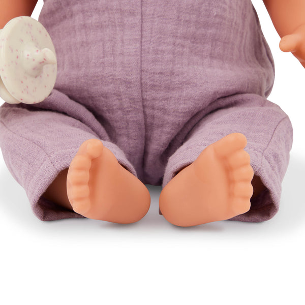 Babypuppe mit Schnuller im lila Musselinoutfit mit Stirnband