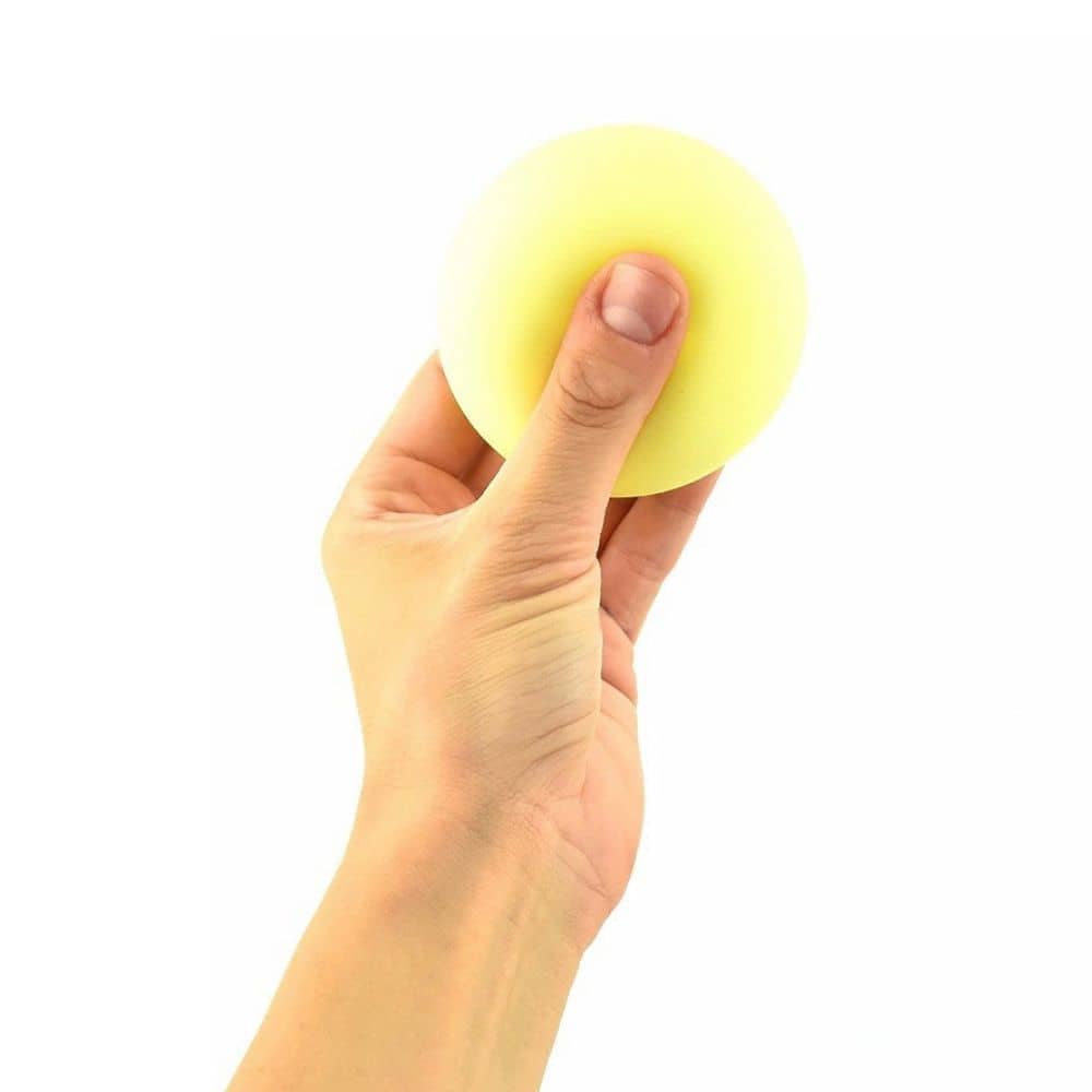 Hand drückt einen gelben Neon-Knautschball, dahinter ein Display Night Glow