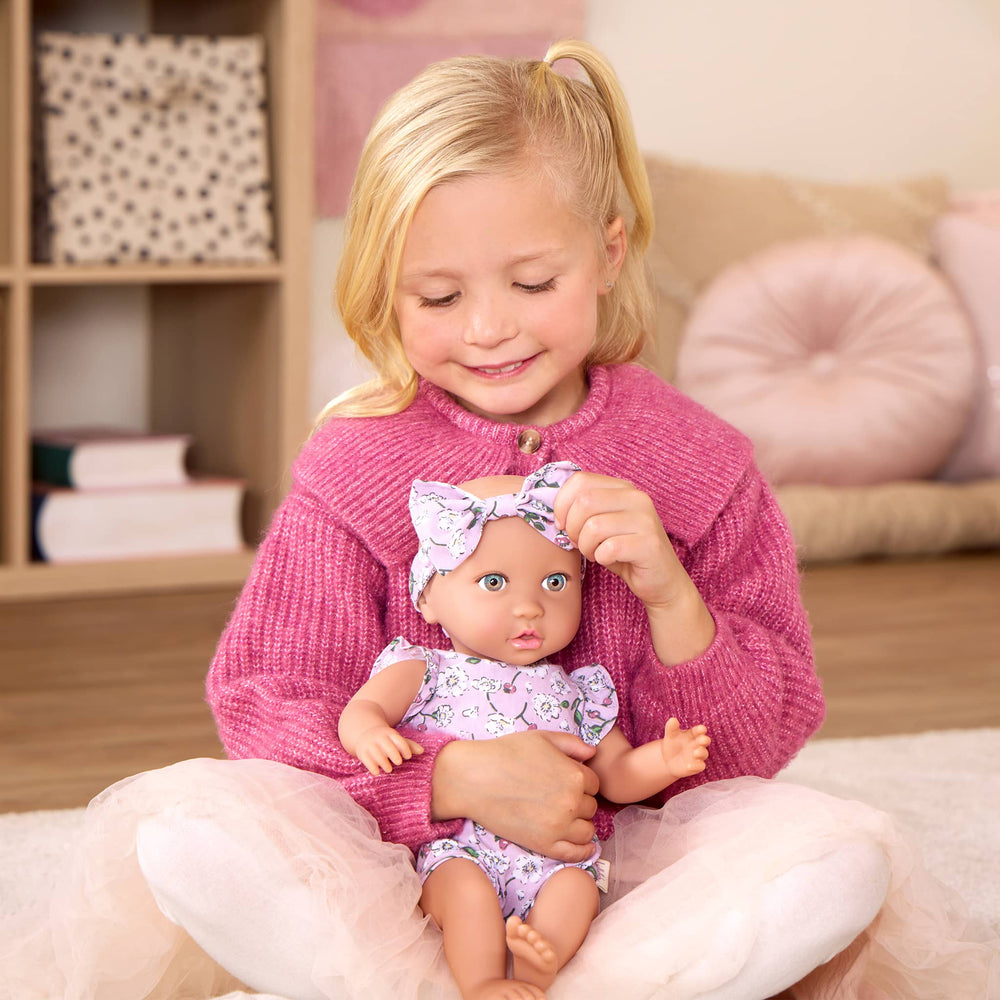 Babypuppe mit Schnuller – in einem Kleidchen mit Blümchenmuster und einem Haarband