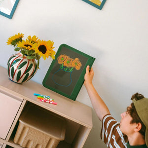 Kind hängt die Neon-Zeichentafel mit Sonnenblumen-Bild an die Wand