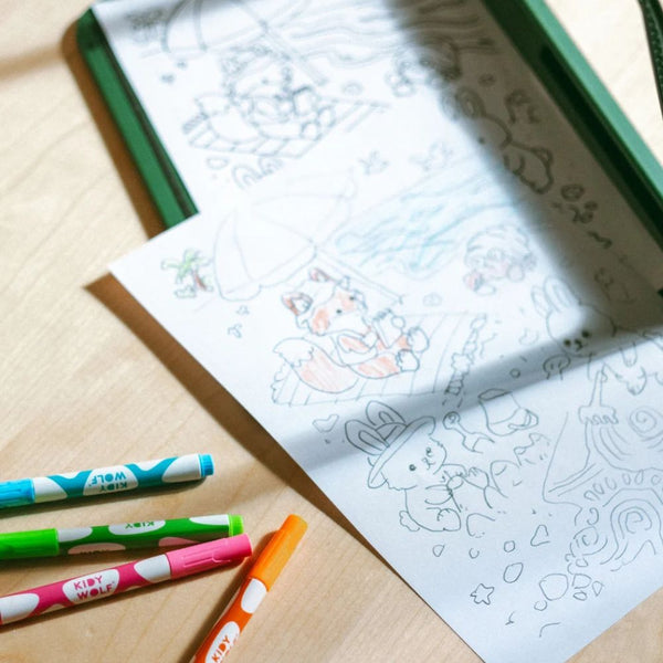Abgepauste Cozy-Zeichnung auf Papier neben bunten Neon-Kreidemarkern