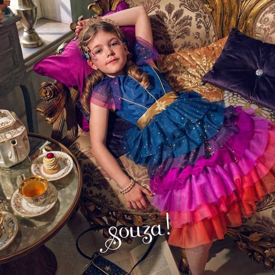 Mädchen im Tüllkleid Dawn liegt auf einem Sofa mit Kissen