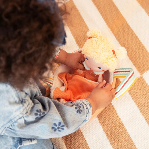 Kind spielt mit der Babypuppe Méla von Lilliputiens im Körbchen