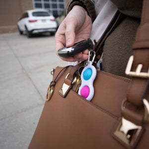 Frau mit einem Dimpl Blasen Schlüsselanhänger kaufen am Handtaschenverschluss in der Stadt.