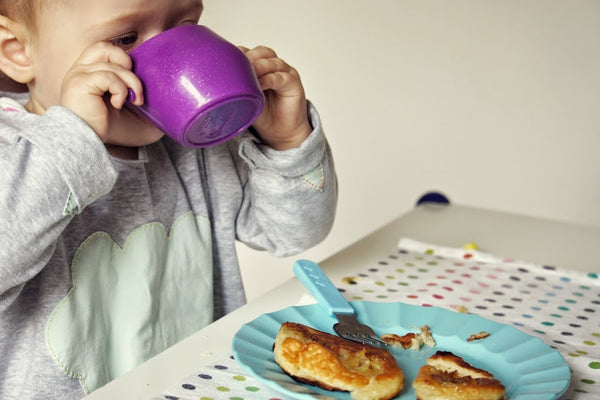 Kleinkind trinkt aus lila Kubek Becher beim Frühstück auf weißem Tisch Doidy Cup grau kaufen