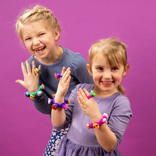 Zwei Mädchen tragen bunte Armbänder und Ringe aus dem Schmuckset Plip Charms – Türkis von Fat Brain Toys