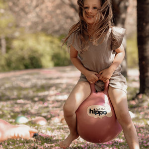 Mädchen mit Hüpfball Rosa von Find that Hippo im Freien auf einer Wiese mit Blumen spielend