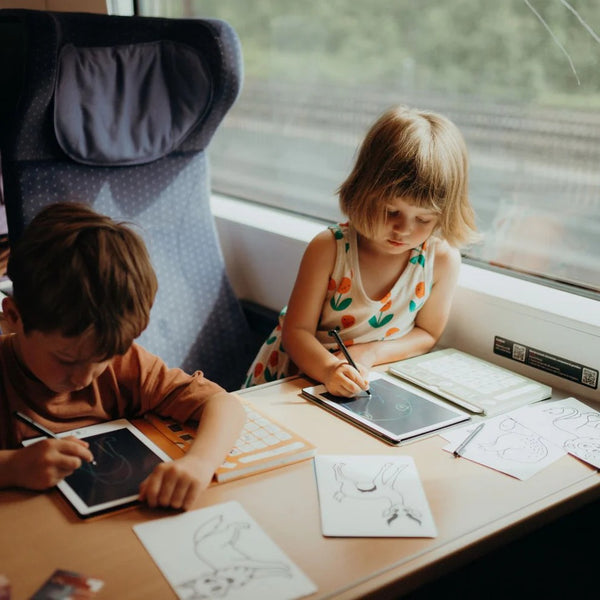 Kinder nutzen das Grafiktablett Kidydraw Mini Galaxie im Zug zum Zeichnen und Malen.