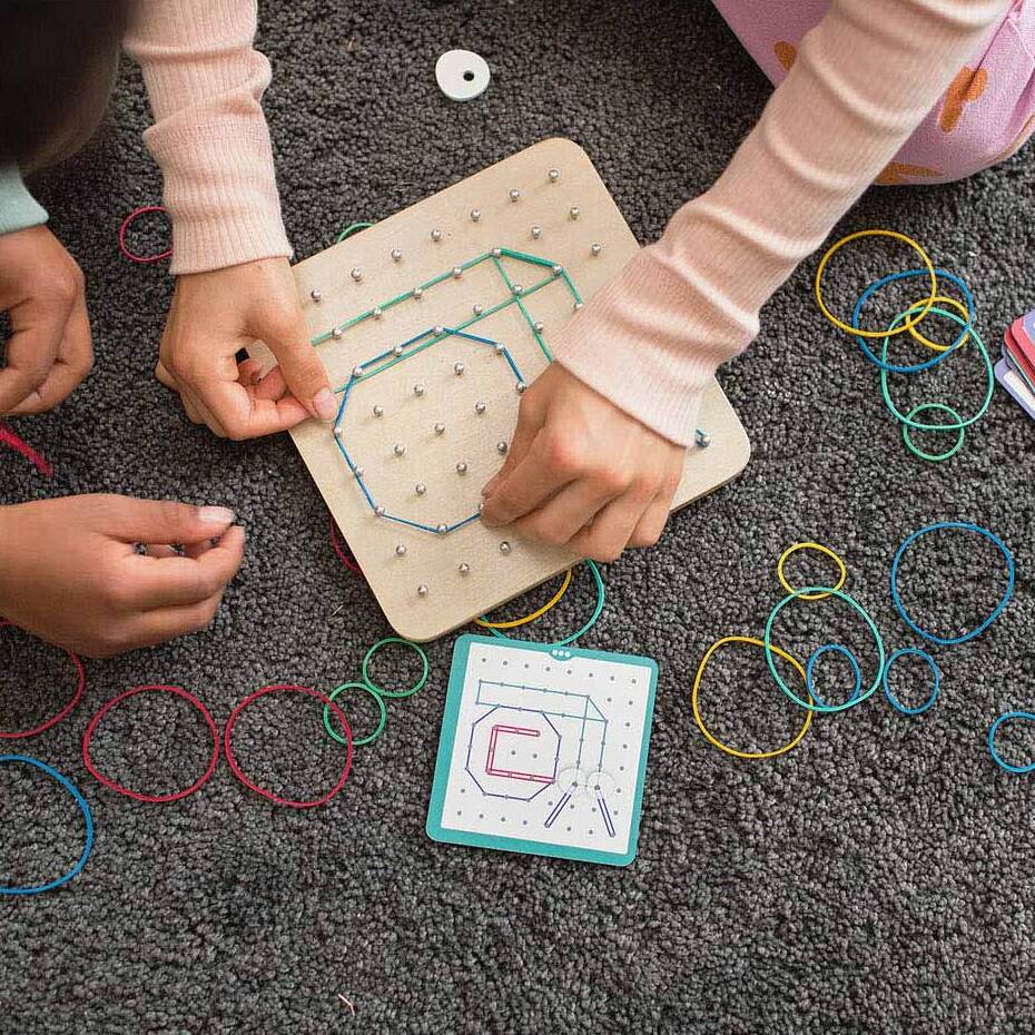 Kind hält Holz Geoboard für Kinder mit bunten Stiften und Gesichtsdesign in den Händen