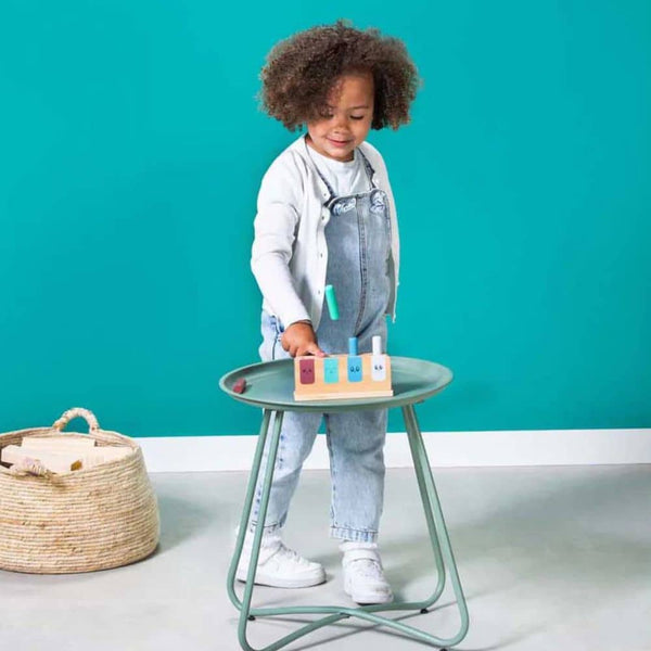 Junge spielt mit BS Toys Holz Geschicklichkeitsspiel Kinder auf einem Tisch vor einer grünen Wand