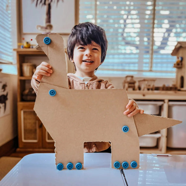 Kind hält Dinosaurier aus Karton gebastelt mit Makedo DIY-Werkzeugset – Play 17-teilig