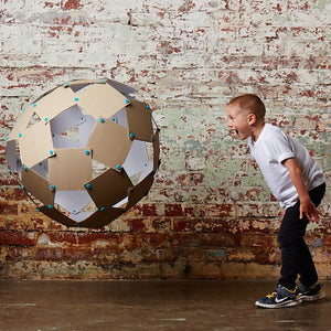 Makedo Zestaw konstrukcyjny mit Ball aus verbundenen Pappstücken, spielendes Kind im weißen T-Shirt