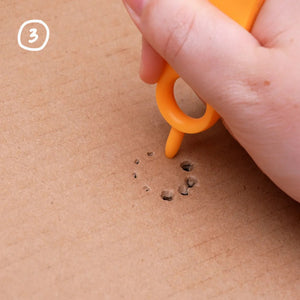Satz von Roto-Ring 16 el mit orangefarbenem Werkzeug, das Löcher in Karton stanzt