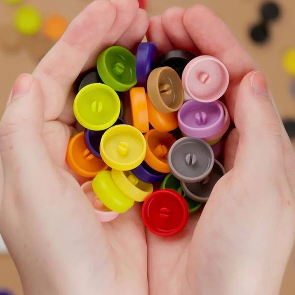 Bunte Makedo Scru-Dot dekorative Schraubenkappen in einer Hand für DIY-Projekte