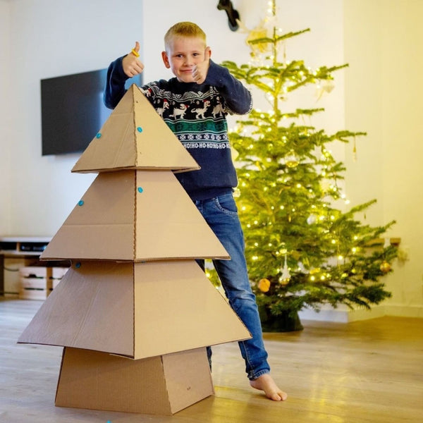 Kind zeigt Daumen hoch neben Karton Tannenbaum gebaut mit Sicherer Kartonperforierroller Fold-Roller