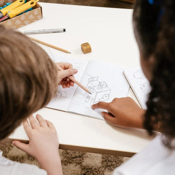 Kinder zeichnen 3D-Formen im Skizzenbuch - 2D und 3D von Makedo auf einem Tisch