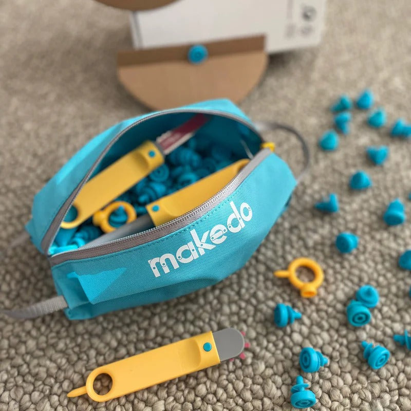 Makedo Tasche für Werkzeuge und Schrauben mit gelbem Werkzeug und blauen Schrauben vor spielendem Kind