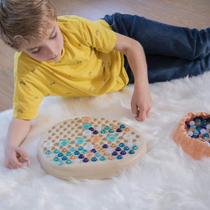 Kind spielt mit dem Puzzle – Mandala-Stein von Miniland auf weißem Teppich