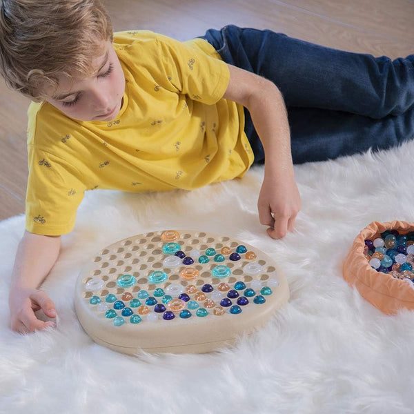 Kind spielt mit dem Puzzle – Mandala-Stein von Miniland auf weißem Teppich
