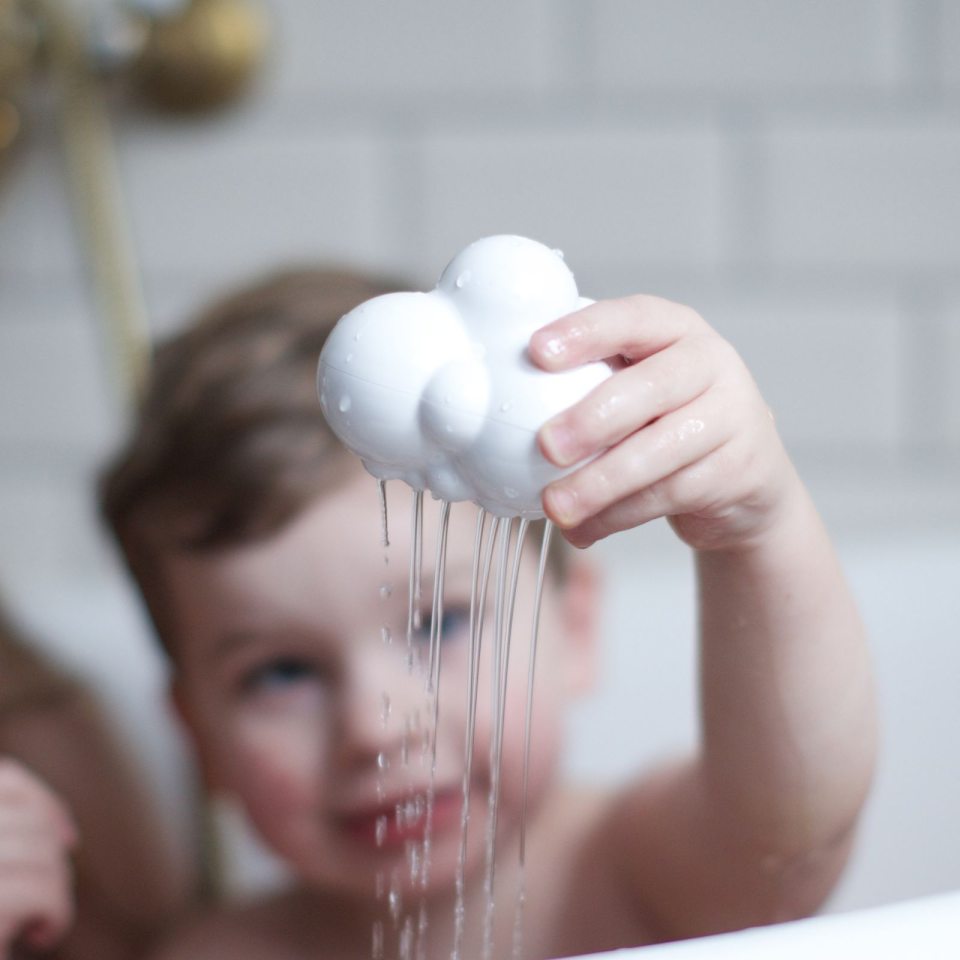 Kind spielt mit Moluk Plui Badespielzeug – Regenwolke in Badewanne mit Wasserfall-Effekt