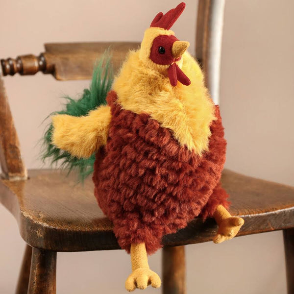 Jellycat Plüsch-Hahn 22 cm mit weichem, buntem Plüschfell sitzend auf Holzstuhl