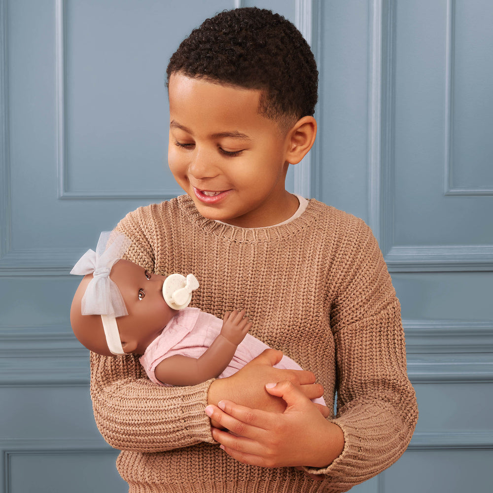 Babypuppe mit Schnuller im rosa Musselinoutfit mit Stirnband