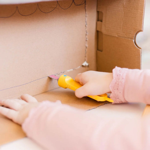 Kind benutzt die Makedo Sichere Säge - Safe-Saw zum Schneiden von Karton in gelbem Werkzeuggriff