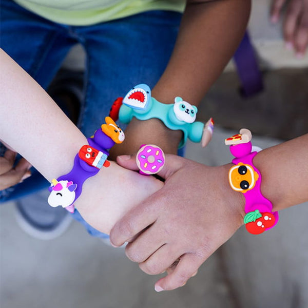 Fat Brain Toys Schmuckset Plip Charms – Rosa mit bunten, tier- und lebensmittelinspirierten Armbändern an Kinderhandgelenken