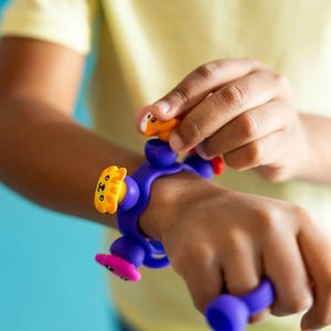 Kind trägt Schmuckset Plip Charms – Violett Armband mit bunten Tierfiguren von Fat Brain Toys