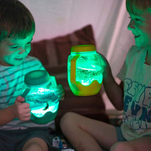 Kinder spielen mit Glo Pals Sensorik-Glas zum Befüllen mit Wasser – hellblau bei gedimmtem Licht