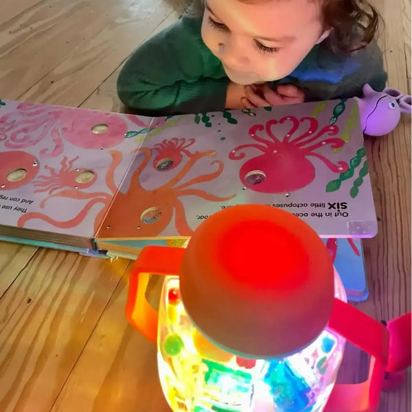 Kind spielt mit Glo Pals Zabawka progresywna und Sensorik-Glas zum Befüllen mit Wasser – rot leuchtet bunt