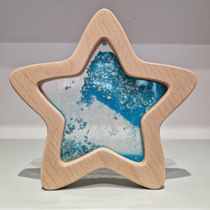 Sensorischer Stern leuchtet im Dunkeln mit glitzerndem Wasser und Holzrahmen für kreative Spielstunden