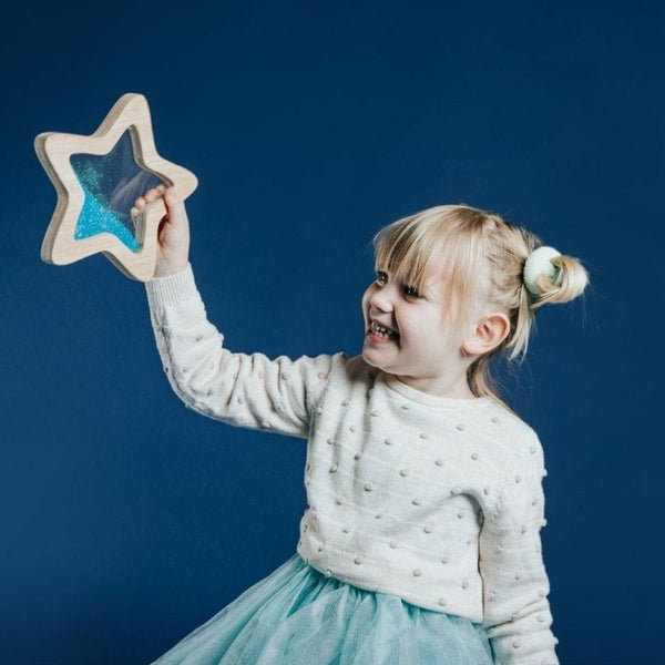 Petit Boum sensorischer Stern leuchtet im Dunkeln mit glitzerndem Inneren, gehalten von einem lachenden Mädchen