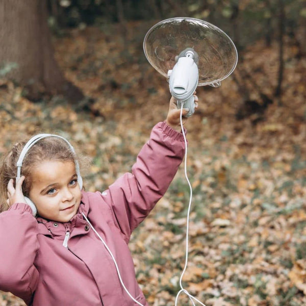 Mädchen mit Kopfhörern verwendet einen Soundverstärker für Kinder im Wald für spannende Geräusche