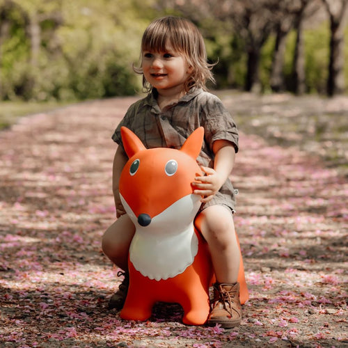 Kind sitzt auf dem orangefarbenen Springer Fuchs von Find that Hippo im Freien
