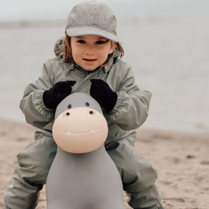 Kind spielt draußen mit dem Springpferd von Find that Hippo, dem Springer Nilpferd, in Grau